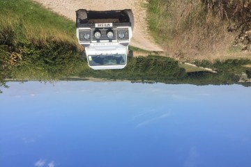 Picture of a white 4x4 Land Rover on a pathway next to a field