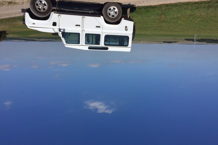 Picture of a white 4x4 Land Rover on a pathway next to a field